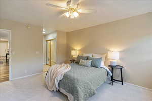 Carpeted bedroom with baseboards, a closet, and a ceiling fan