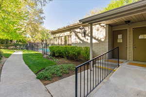 View of exterior entry featuring fence, a fenced in pool, brick siding, and a lawn