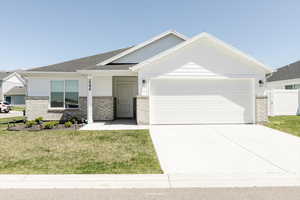 View of front of home featuring a front lawn, fence, brick siding, an attached garage, and driveway