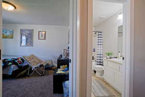 Bedroom featuring light carpet, connected bathroom, a sink, and a textured ceiling