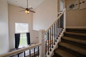 Staircase featuring high vaulted ceiling, a ceiling fan, and recessed lighting