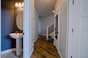 Hallway with wood finished floors, baseboards, a sink, and a textured ceiling