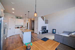 Kitchen with a sink, stainless steel appliances, recessed lighting, open floor plan, and white cabinets
