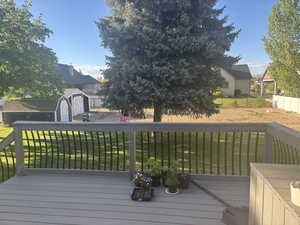 Wooden terrace with a lawn, an outbuilding, a residential view, and a storage shed