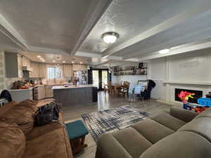 Living room featuring beamed ceiling, light wood finished floors, french doors, and a fireplace with raised hearth