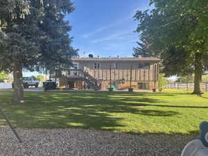 Back of house featuring a lawn, a deck, stairway, and fence