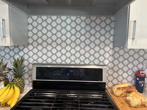 Interior details featuring white cabinetry, light countertops, tasteful backsplash, and range with gas cooktop