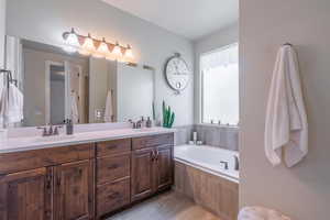 Full bathroom with a sink, double vanity, a garden tub, and tile patterned floors