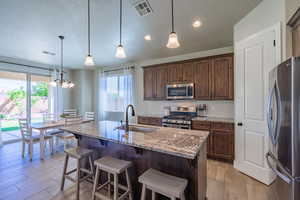 Kitchen with appliances with stainless steel finishes, plenty of natural light, light stone countertops, and a sink