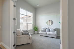Sitting room with baseboards, a healthy amount of sunlight, visible vents, and carpet