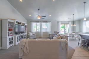 Living room featuring baseboards, ceiling fan with notable chandelier, lofted ceiling, and recessed lighting