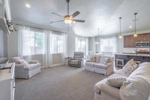 Living area with light colored carpet, baseboards, a ceiling fan, and visible vents