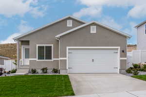 Ranch-style house with driveway, stucco siding, a front yard, and an attached garage