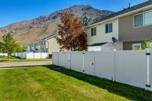 View of side of home with a yard, a residential view, a mountain view, and fence
