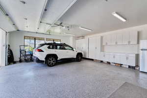 4-car garage with two EV charger stations, storage cabinets, workbench, and epoxy floor