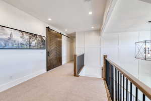 Upstairs corridor featuring recessed lighting, a barn door, high-end carpet, and board and batten decorative wall