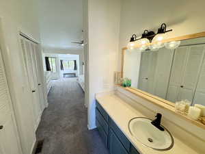 Bathroom featuring a closet, baseboards, ceiling fan, visible vents, and vanity