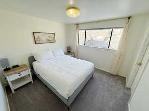 Bedroom featuring baseboards and dark carpet