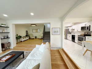 Living area with stairway, baseboards, visible vents, arched walkways, and recessed lighting