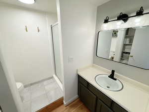 Full bath featuring a stall shower, vanity, toilet, and baseboards