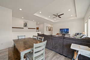 Dining area with a tray ceiling, light wood-style floors, a ceiling fan, and recessed lighting