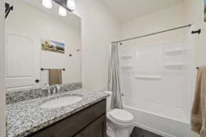 Bathroom with shower / tub combo with curtain, vanity, and toilet