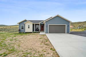 Ranch-style home featuring an attached garage, a mountain view, and driveway