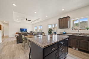 Kitchen featuring a sink, a center island, plenty of natural light, and stone counters