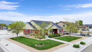 View of front of house featuring concrete driveway, a front lawn, a residential view, and stone siding