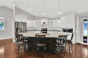 Kitchen with backsplash, a spacious island, light countertops, and a sink