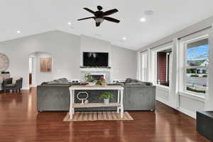 Living room featuring hardwood / wood-style floors, vaulted ceiling, a fireplace, and arched walkways