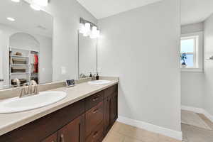Bathroom with a sink, double vanity, a walk in closet, and visible vents