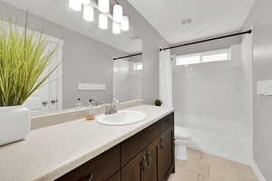 Bathroom featuring vanity, toilet, shower / bath combo with shower curtain, and visible vents