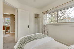 Bedroom featuring a closet, carpet floors, baseboards, arched walkways, and wine cooler