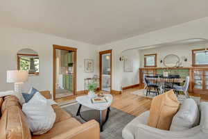 Living room featuring arched walkways, a healthy amount of sunlight, and light wood-type flooring