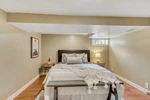 Bedroom with light wood finished floors, baseboards, and visible vents