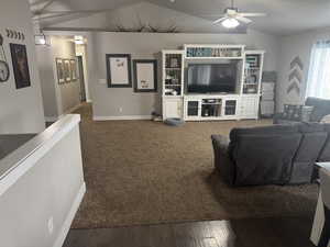 Living room featuring vaulted ceiling, baseboards, a ceiling fan, and dark wood-style floors