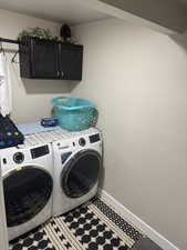 Laundry room featuring separate washer and dryer, cabinet space, and baseboards