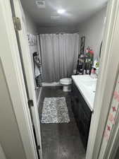 Bathroom with toilet, curtained shower, visible vents, concrete flooring, and vanity