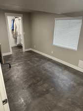 Unfurnished bedroom with a walk in closet, baseboards, a closet, and concrete floors