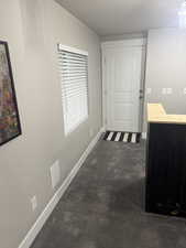 Corridor featuring a textured ceiling, baseboards, and concrete floors