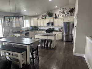 Kitchen featuring a kitchen island, lofted ceiling, decorative backsplash, and appliances with stainless steel finishes