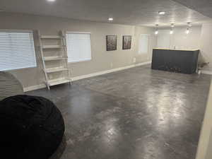 Basement with bar, a textured ceiling, baseboards, and recessed lighting