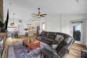 Living room with visible vents, ceiling fan, arched walkways, light wood-style floors, and lofted ceiling