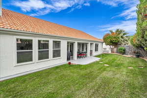 Back of property with stucco siding, a tile roof, fence, a yard, and a patio area