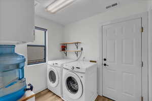 Laundry area featuring separate washer and dryer, laundry area, light wood-type flooring, and visible vents