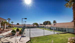 View of tennis court featuring a yard, fence, and a residential view