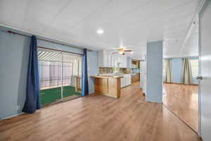 Kitchen featuring a peninsula, light countertops, decorative backsplash, and light wood-style flooring