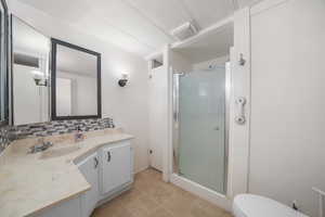 Bathroom with vanity, toilet, tasteful backsplash, and a shower stall