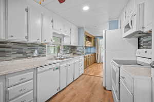Kitchen with a sink, white appliances, light countertops, and light wood-type flooring
